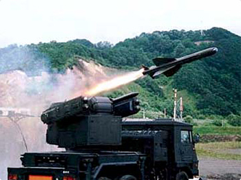 an army missile launches fire while a military vehicle passes