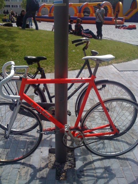 two bikes are parked on the sidewalk next to a pole