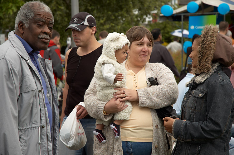 group of people standing in a crowd with one holding a child
