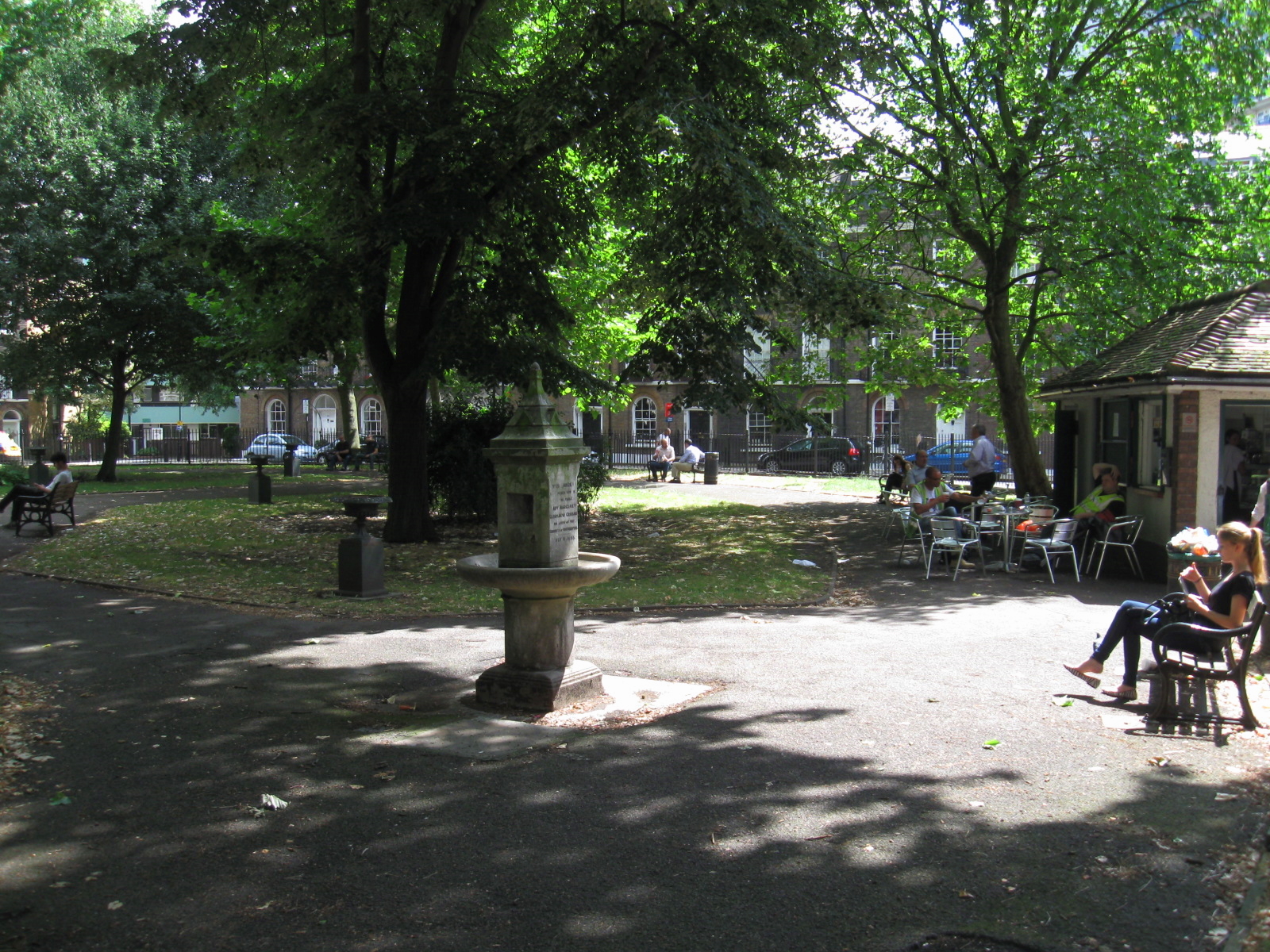 people sitting on benches near a park with lots of trees