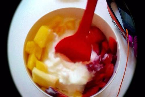 a bowl with fruit, yogurt and a spoon