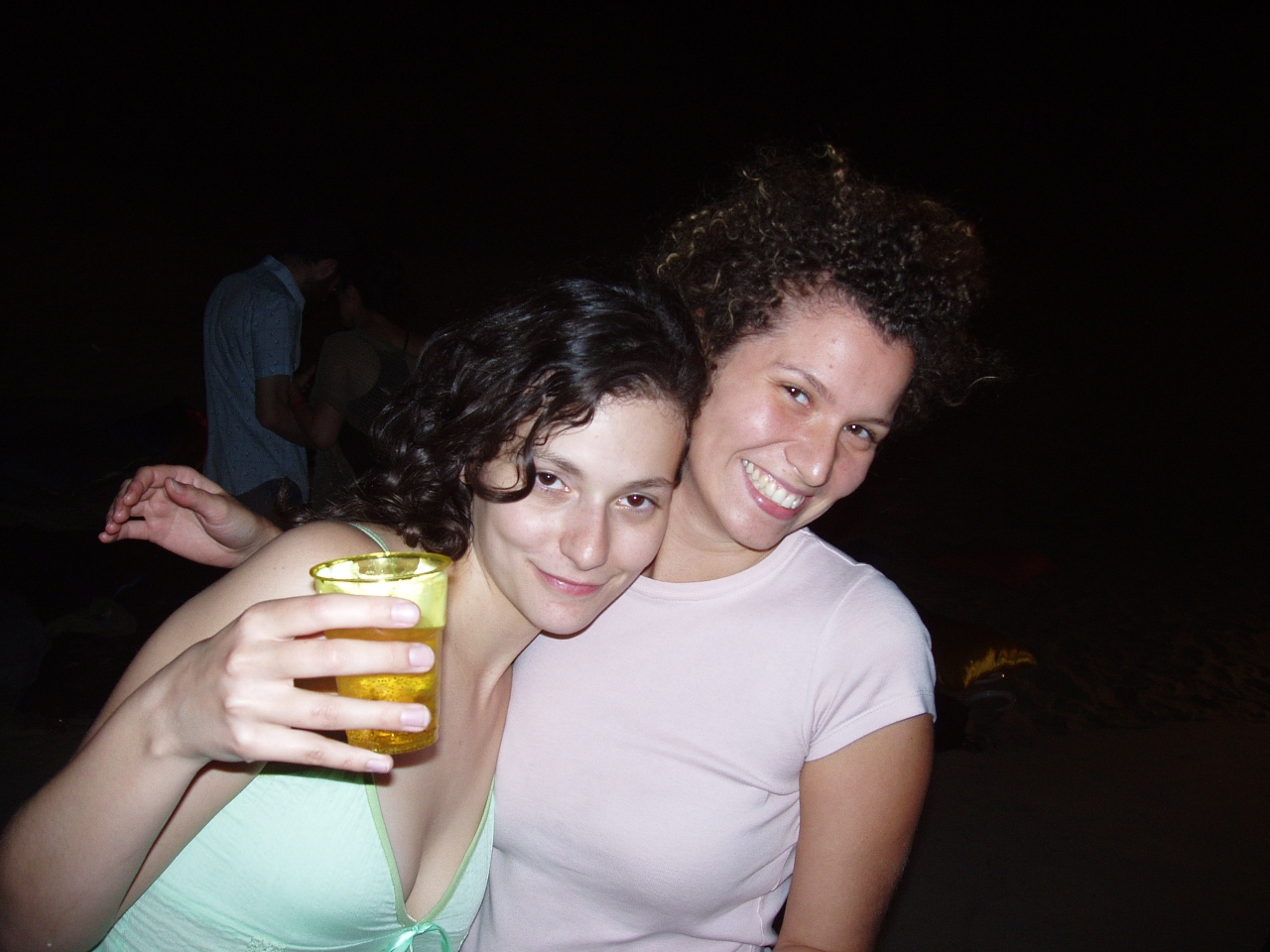 two women standing next to each other posing with drinks