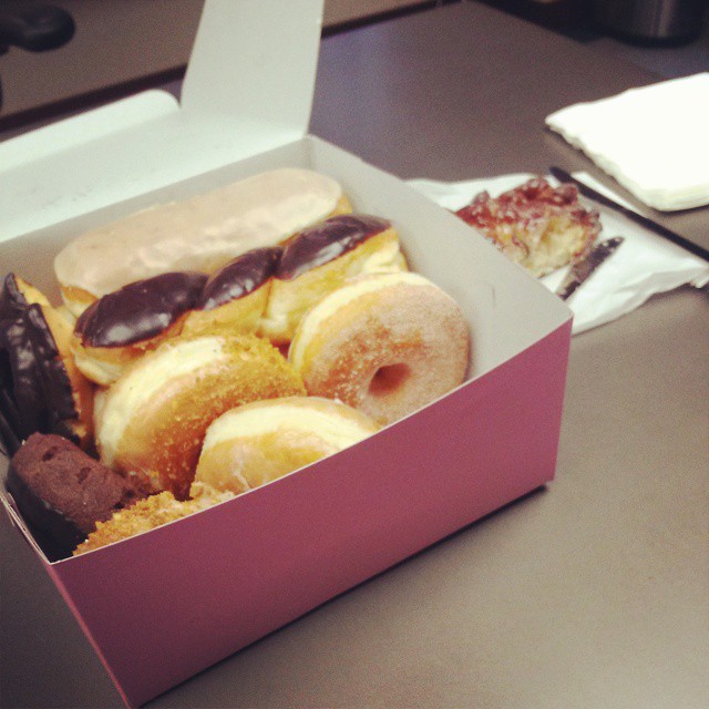 a pink box with assorted donuts inside sits on a counter