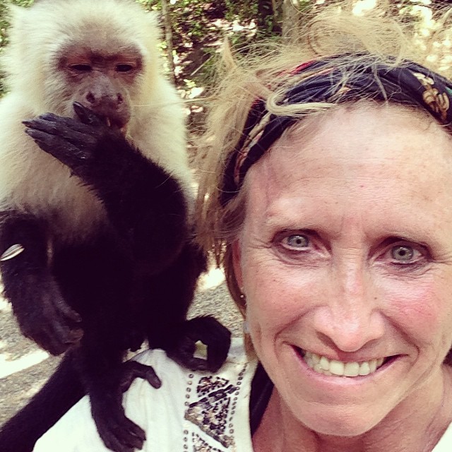 a woman posing for the camera while with two monkeys