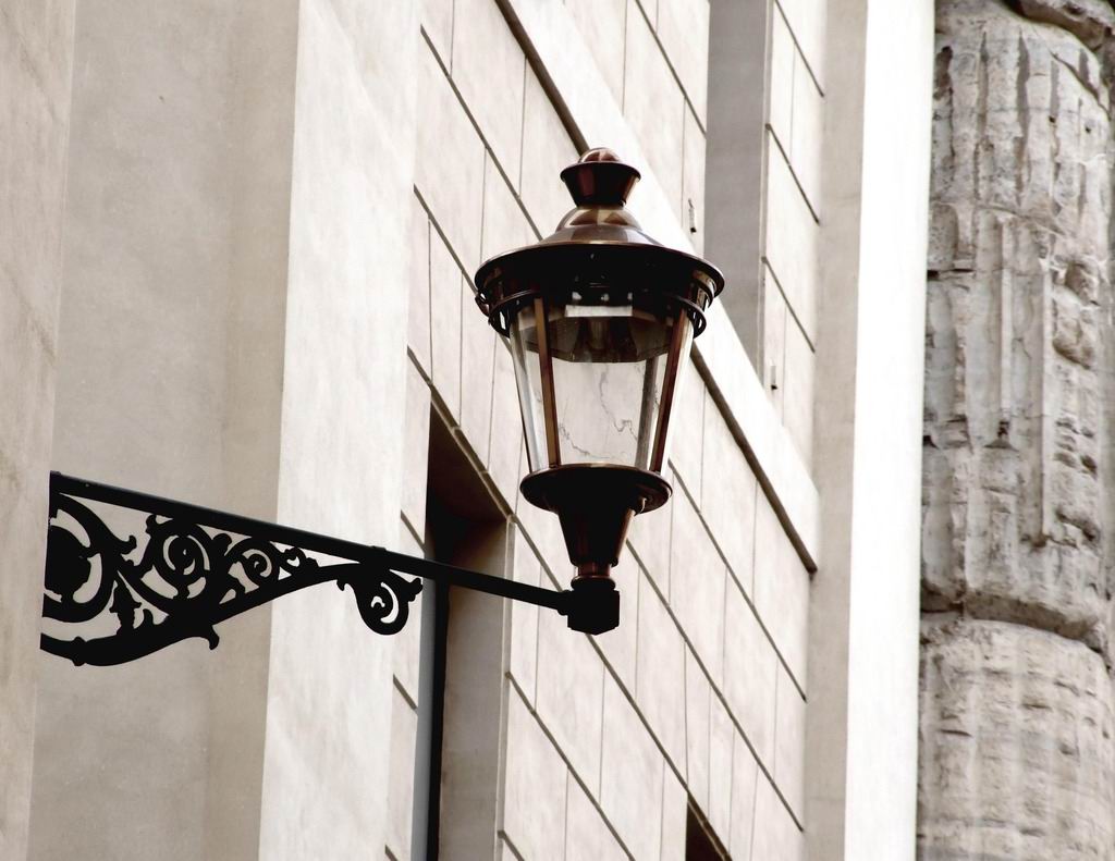 an iron street light on the side of a building