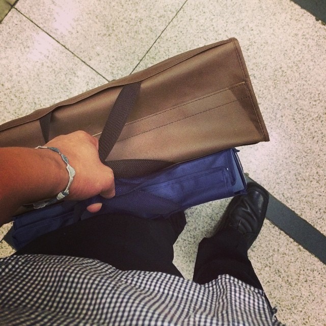 the arm of a person who is holding a brown piece of luggage