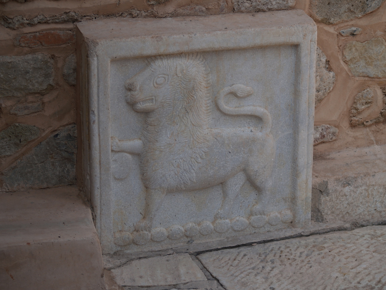 an ornamental, stone lion piece mounted to a wall