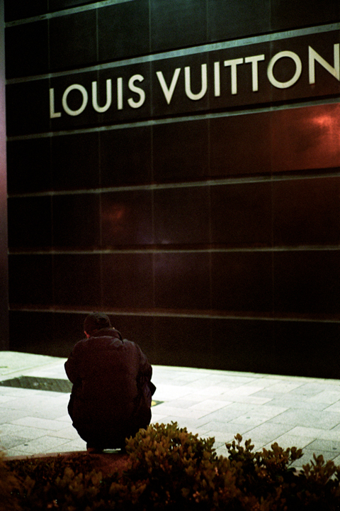 a person sitting on the ground under a sign
