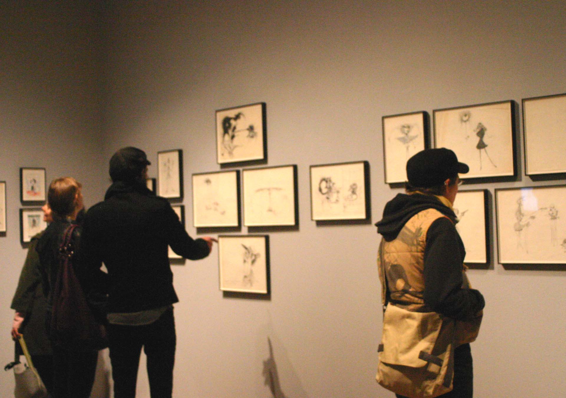 three women standing in front of wall with drawings on it