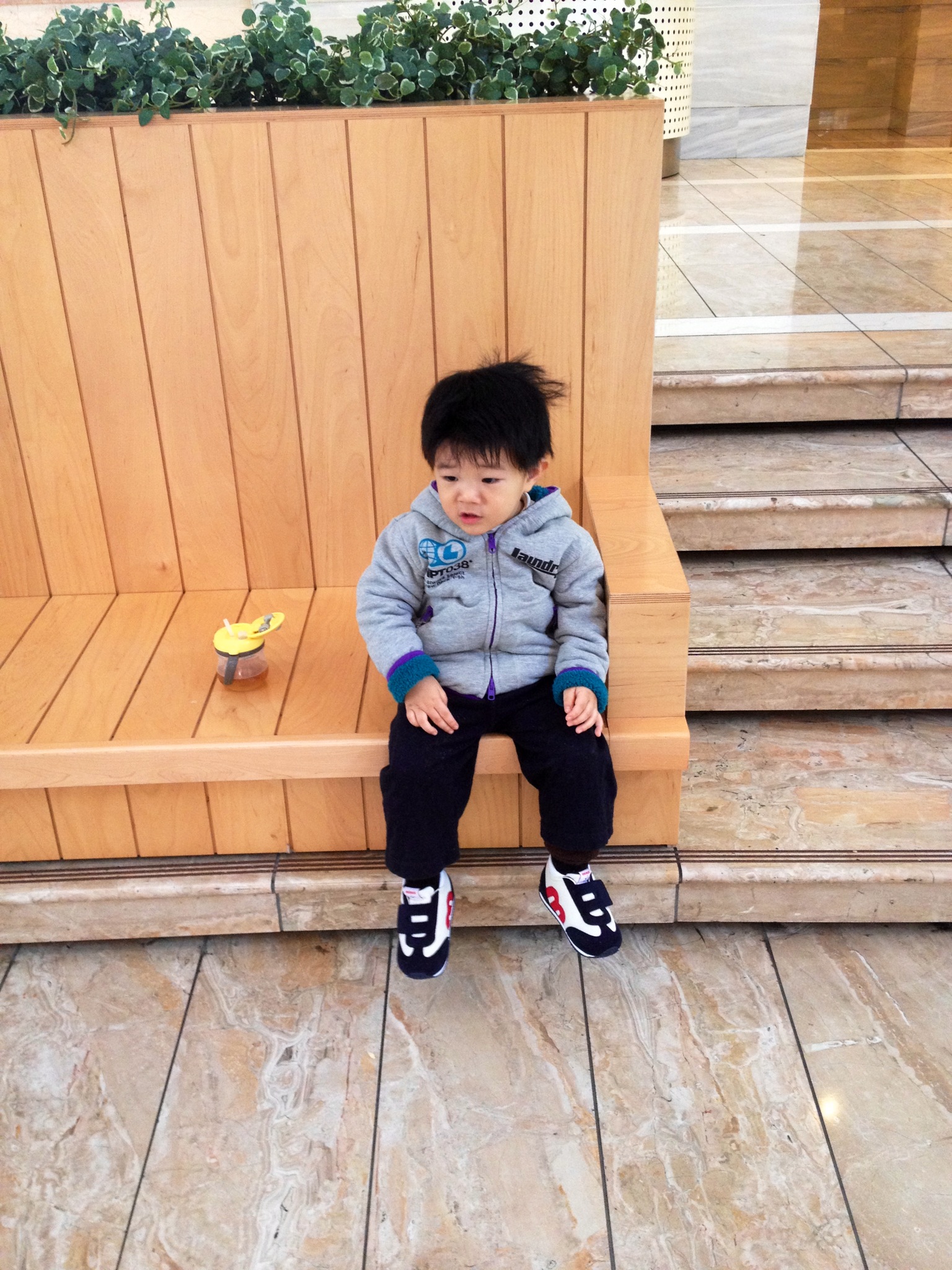 a little boy sitting on a wood bench