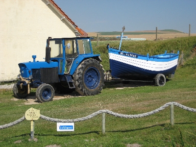 a tractor with a blue boat on the back