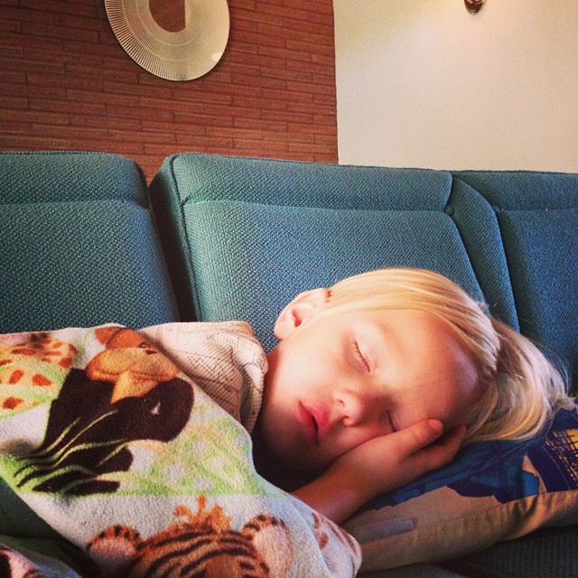 a little boy laying on top of a couch next to a pillow