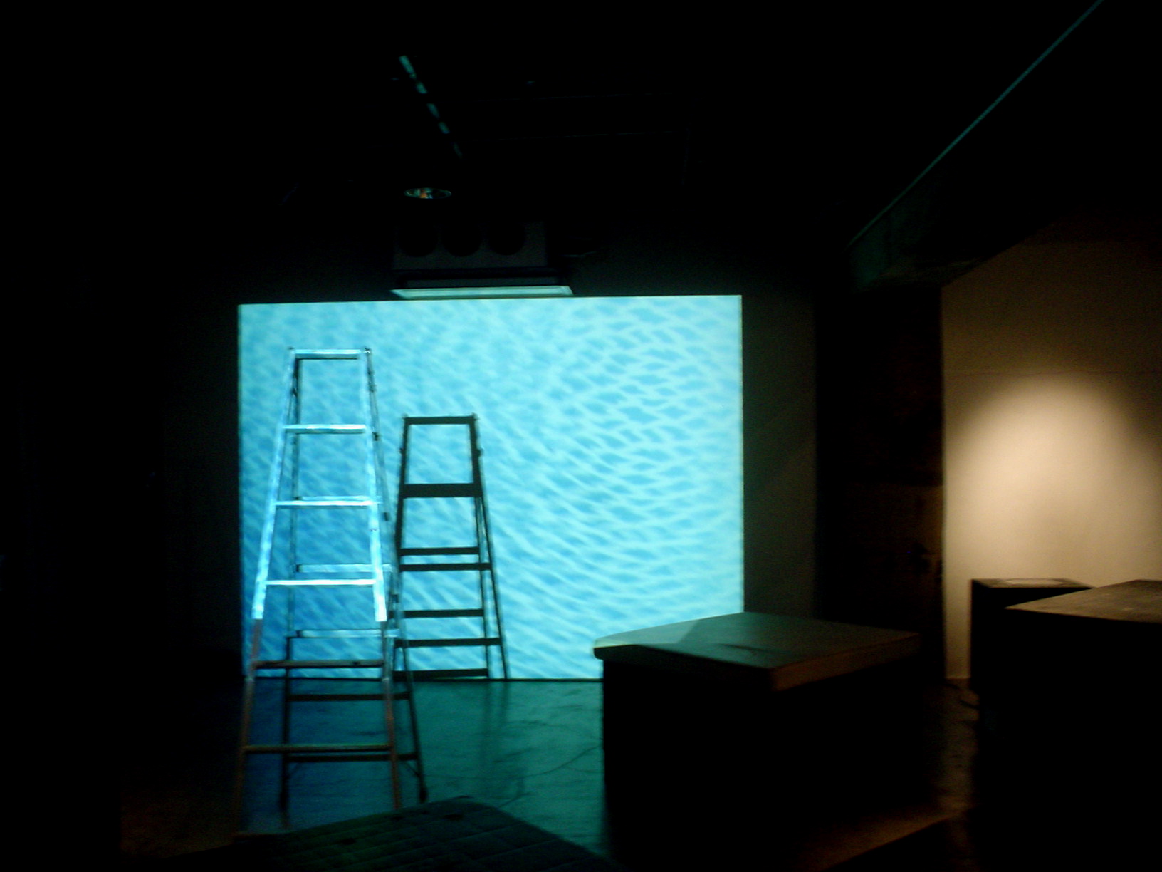 two ladders standing in the dark and a projection of blue water