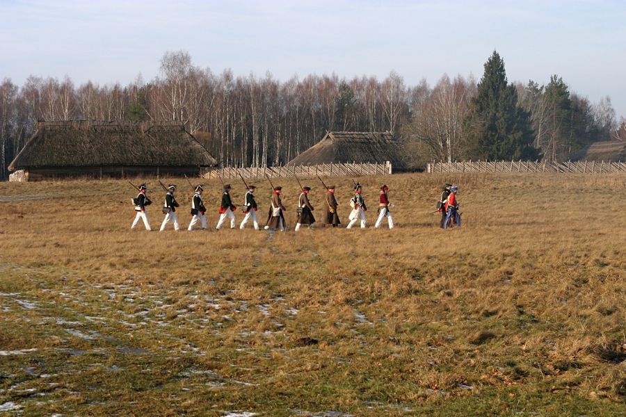 a group of people walking across a lush green field