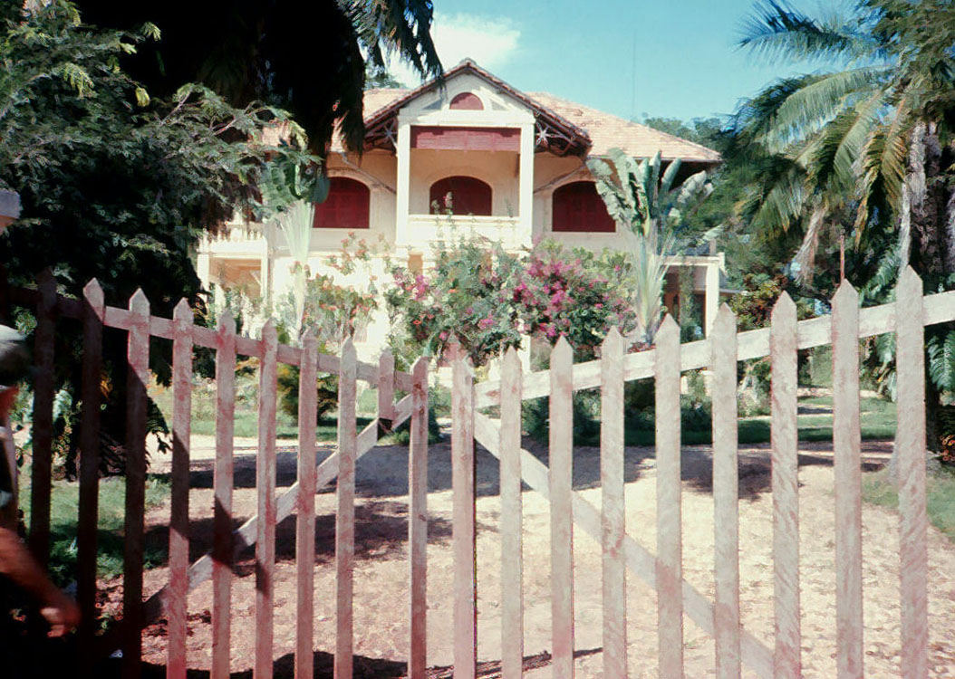 an old style white house with a wooden fence