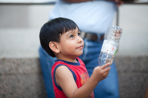 a little boy holds a large plastic water bottle