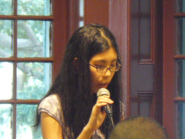 a woman with glasses sitting in front of a microphone