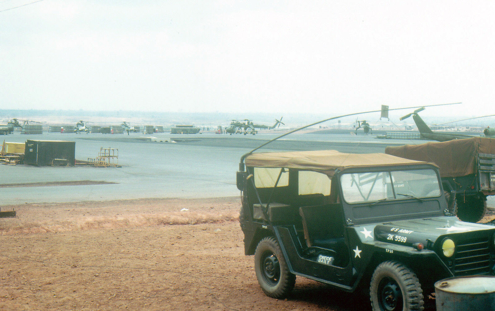 a jeep driving on dirt next to an airplane and some water