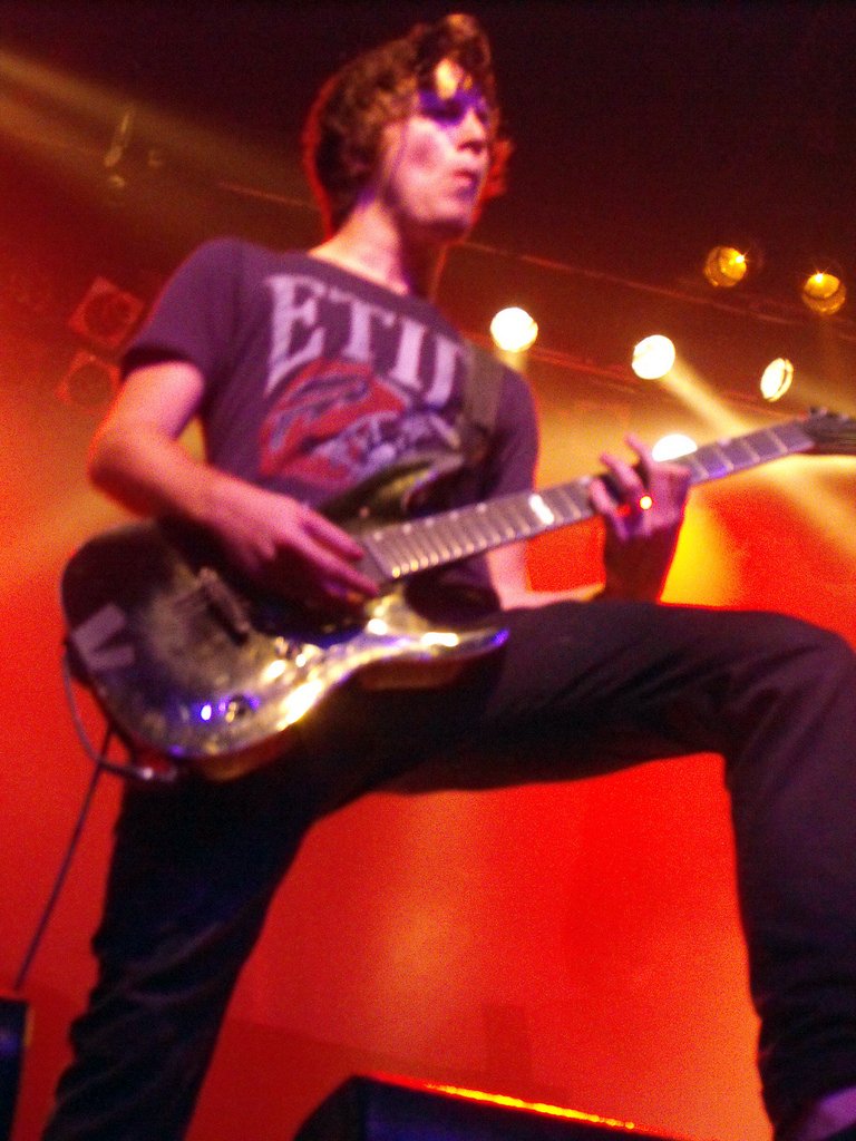 a man with his foot in the air while playing an electric guitar