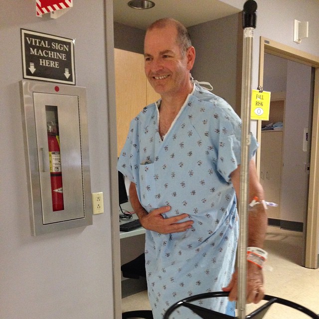 a man in hospital gown standing next to an open door