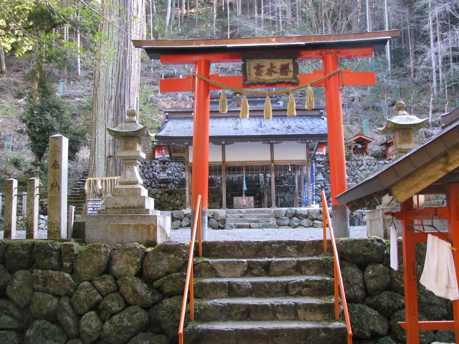 a red shrine with steps to it with the top of it in an area that appears to be surrounded by a large rock wall