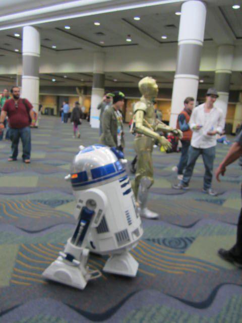 star wars character dressed up in a suit and robot costume with other people