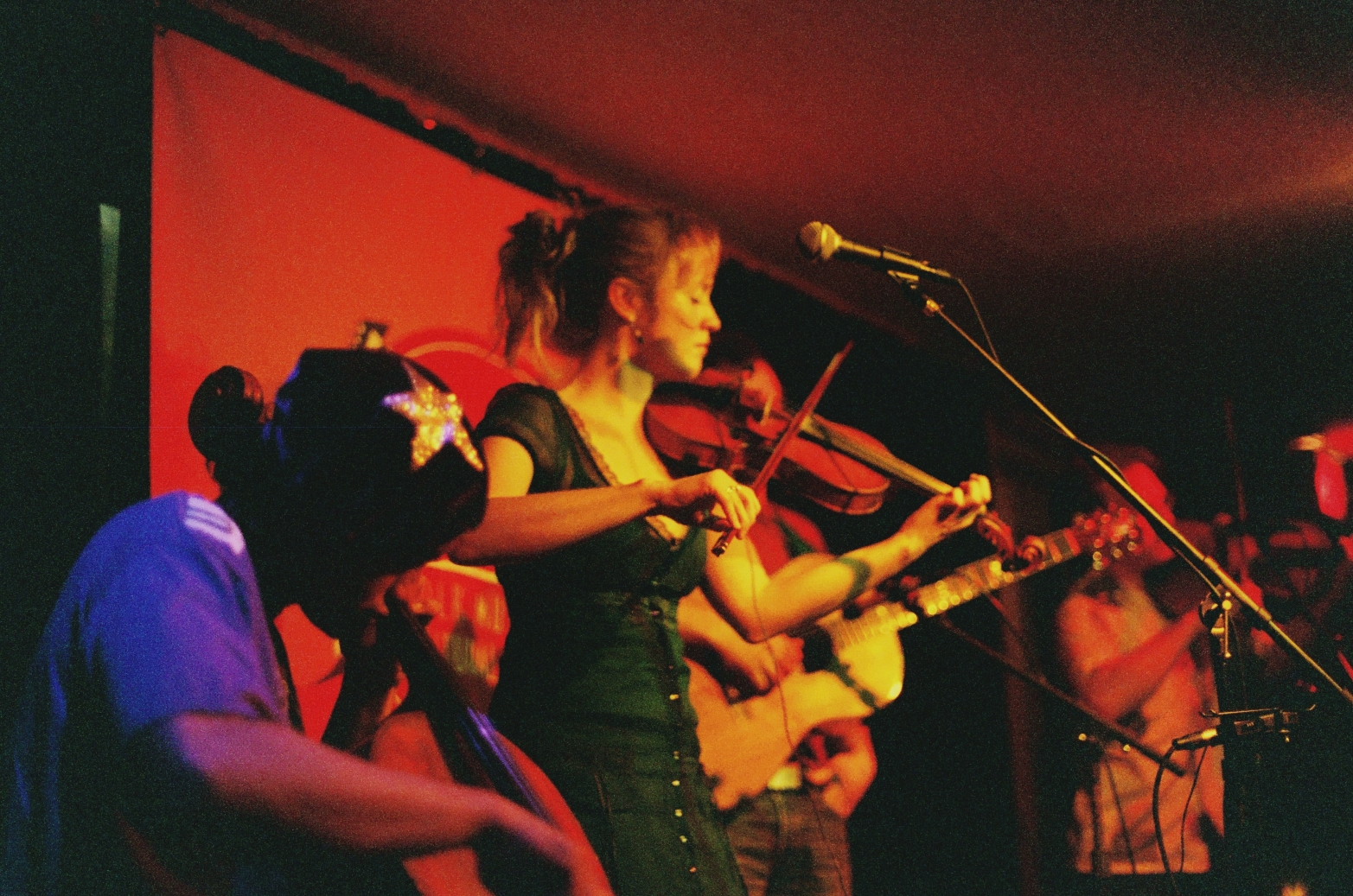 woman in green dress playing violin while other people are watching