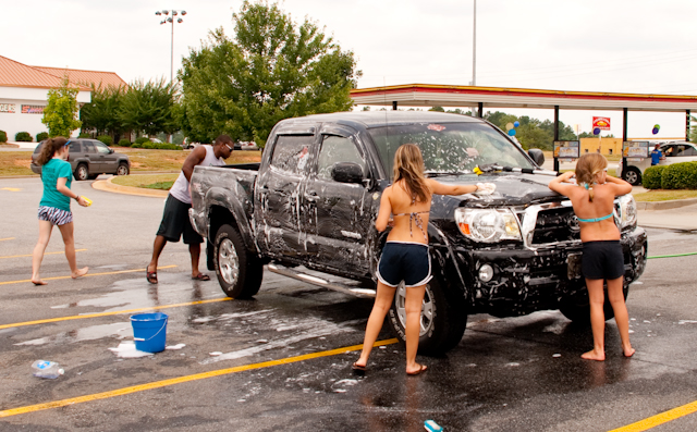 two girls getting wet by a pickup truck