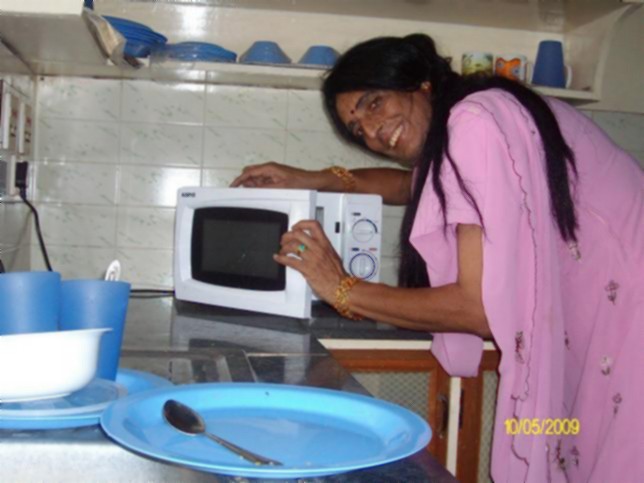 woman smiling with a white microwave oven and blue dishes