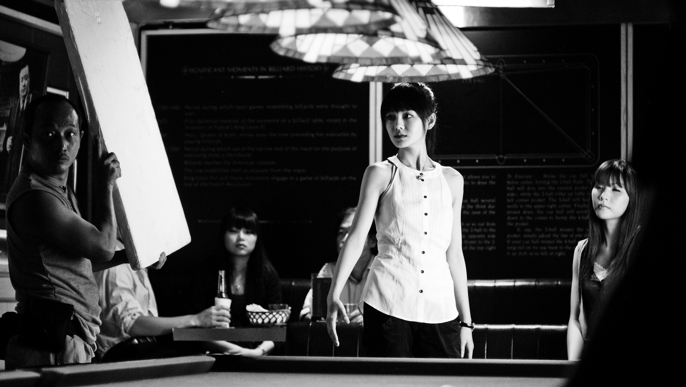 some women are playing pool while one girl stands