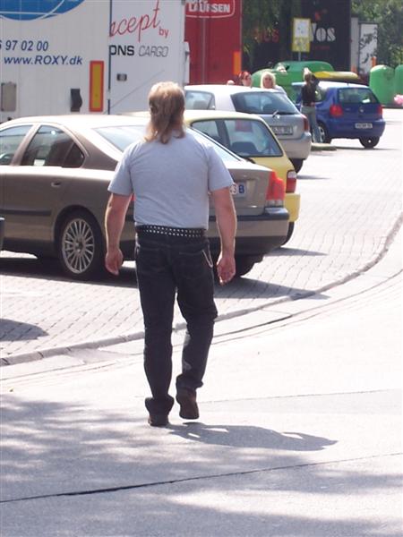 a man is walking on the sidewalk in front of parked cars