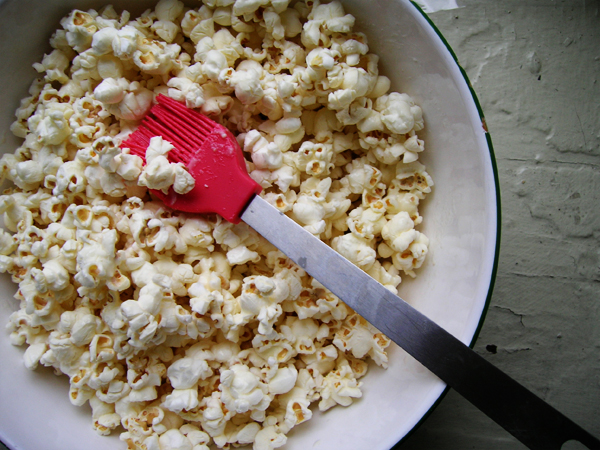 there is a large bowl with popcorn and a red spatula