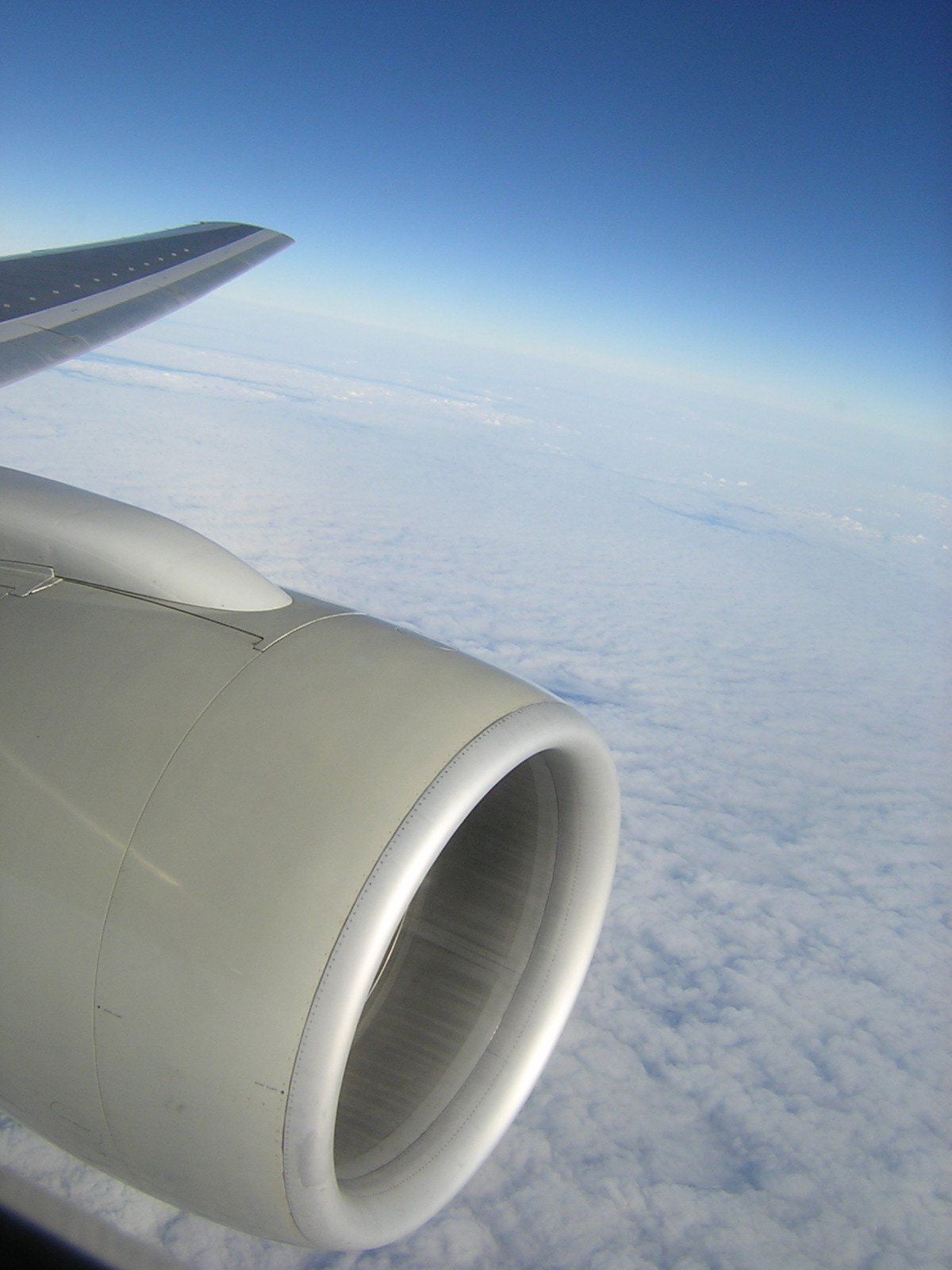 an airplane window, looking out at a cloud filled sky