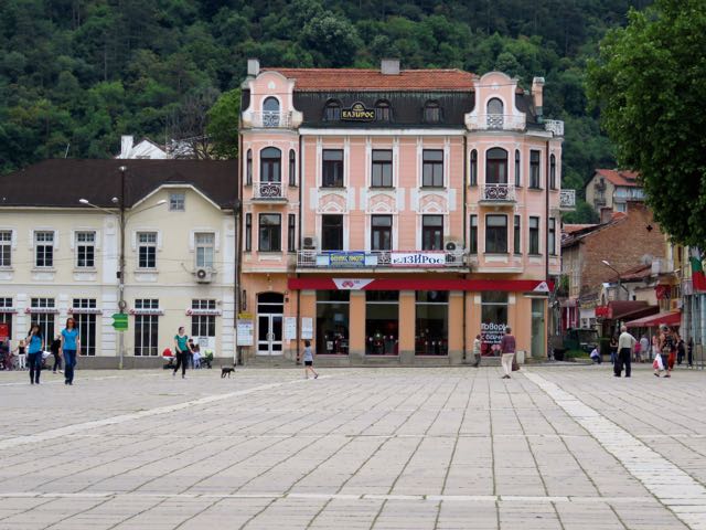 several buildings on a square in front of mountains