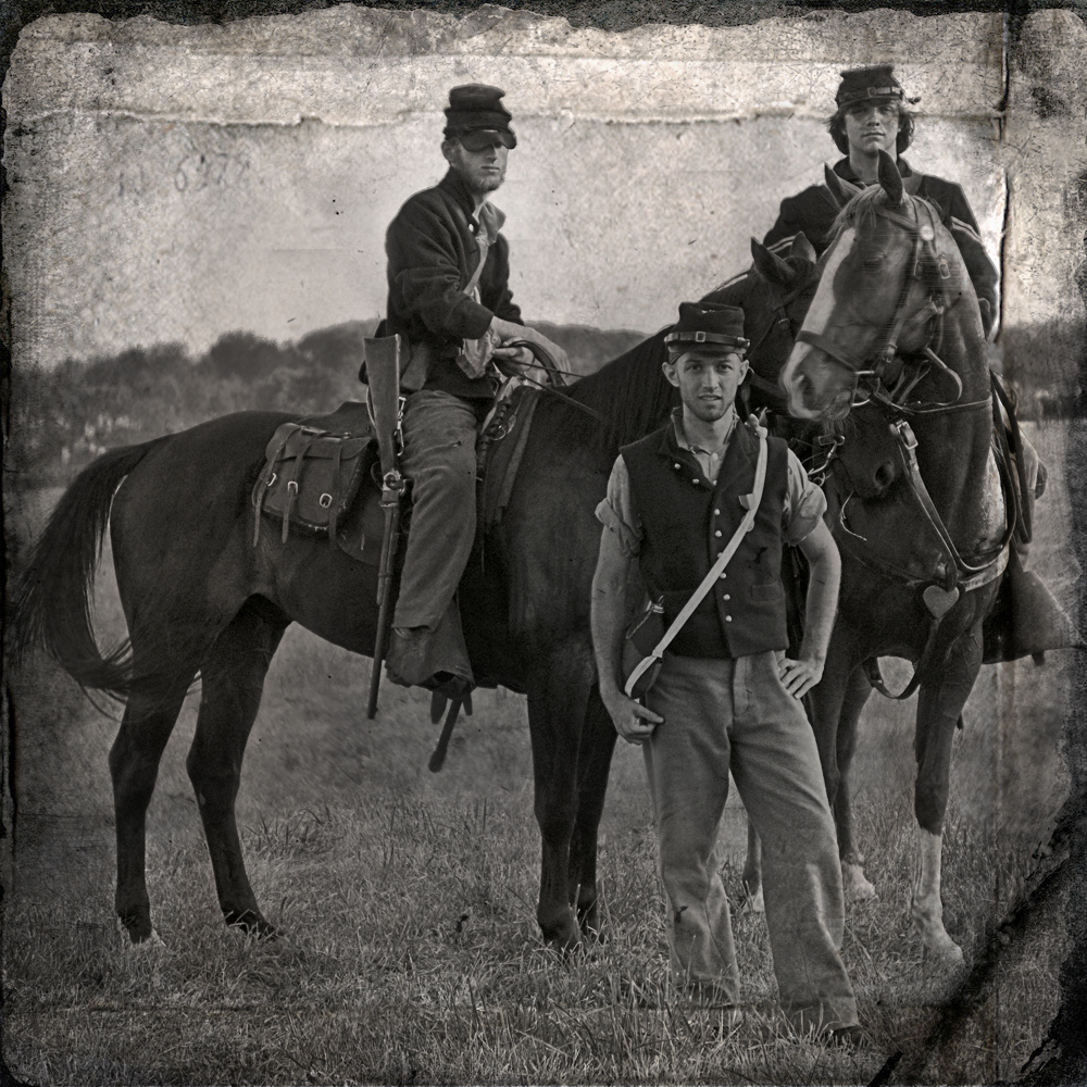 three men are posing on horseback in the field