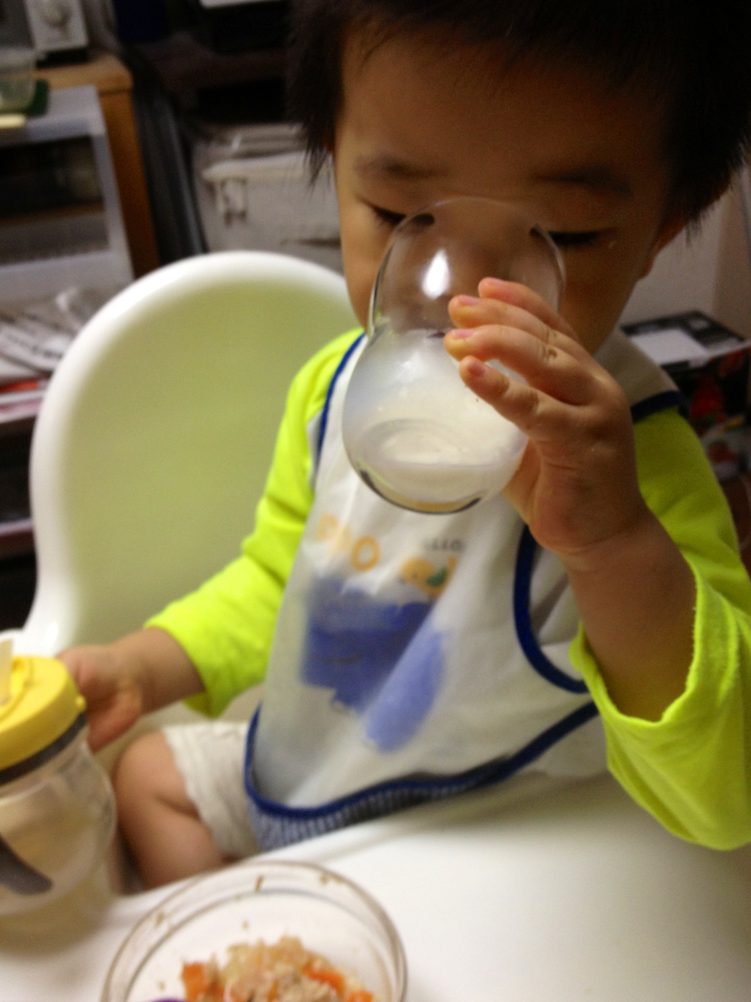 a small child drinks milk from a glass