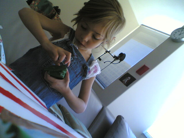 the little girl is playing with her green camera
