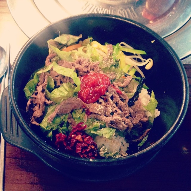 a bowl filled with lots of salad sitting on top of a wooden table