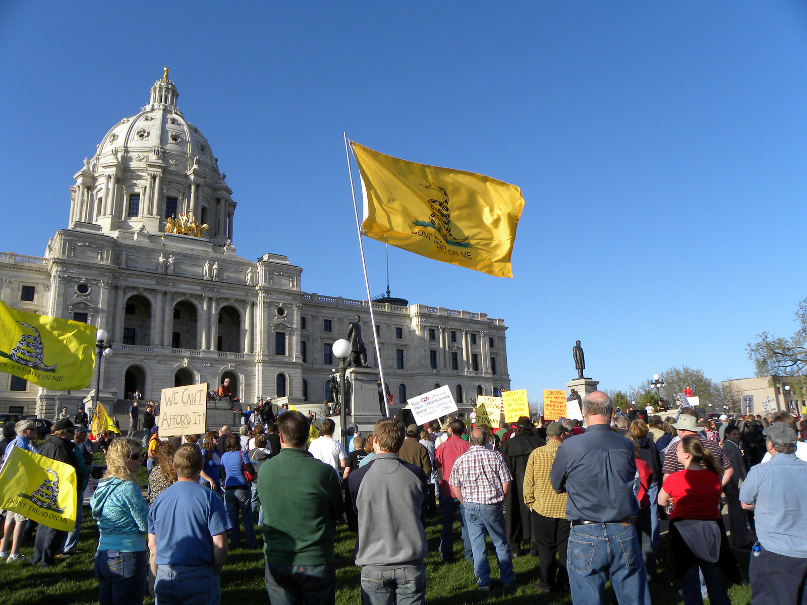 a protest outside a city building in the background with flags and banners