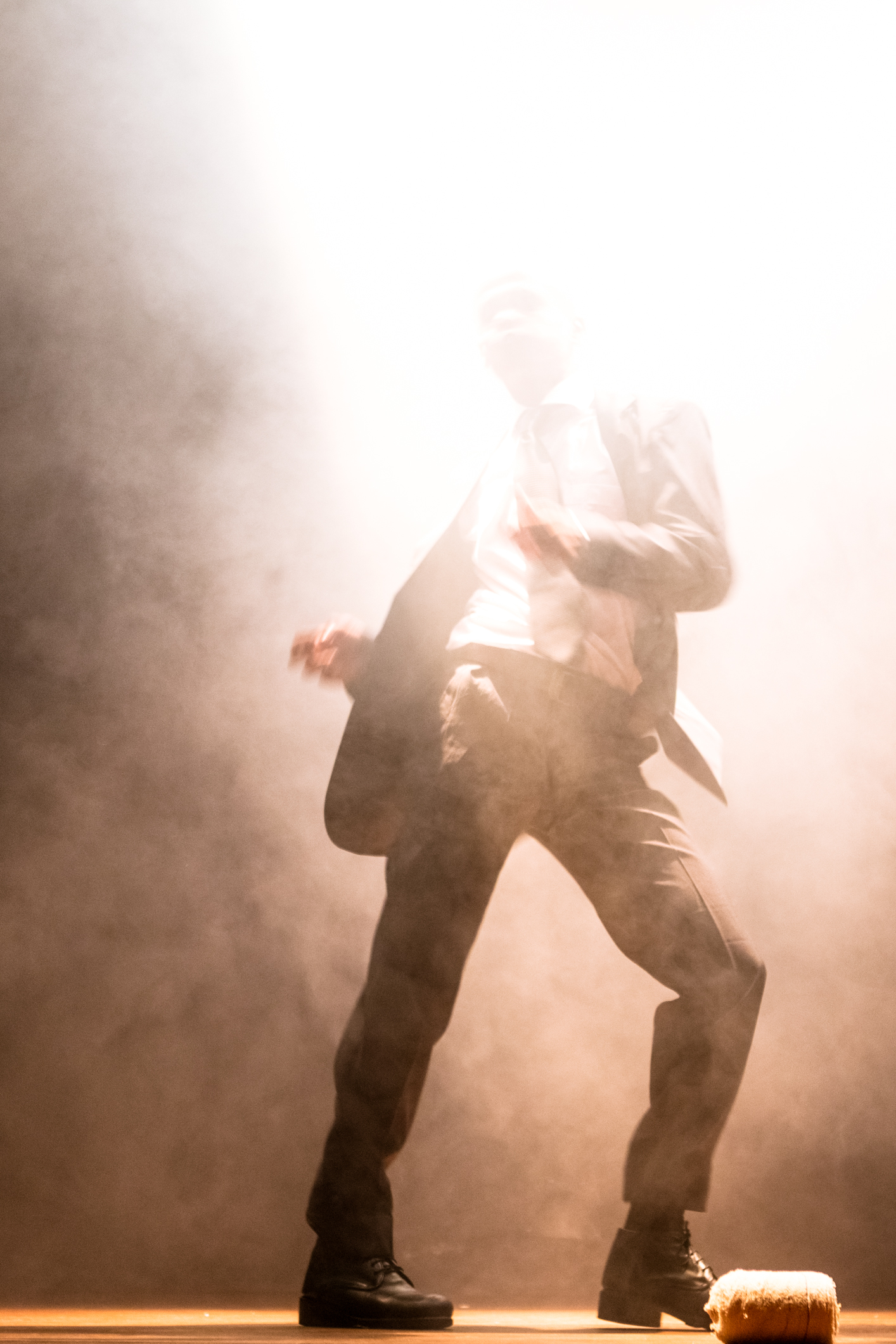 a man wearing pants and boots is standing on stage