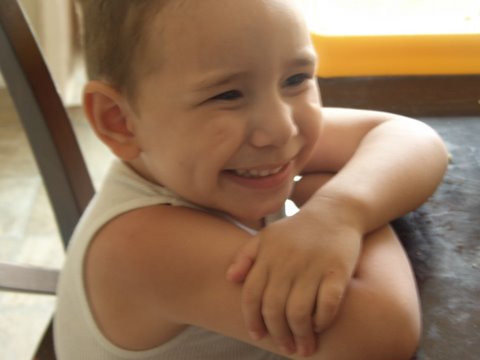 a young child smiling while sitting in a chair