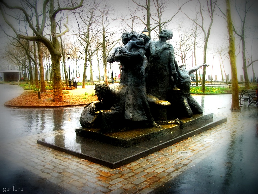 two statue statues near a park covered in trees