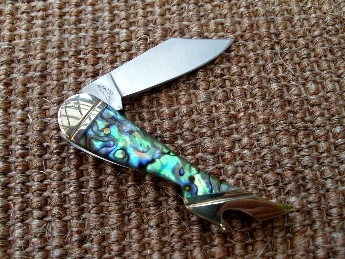 a knife with colorful shells in it lying on a table