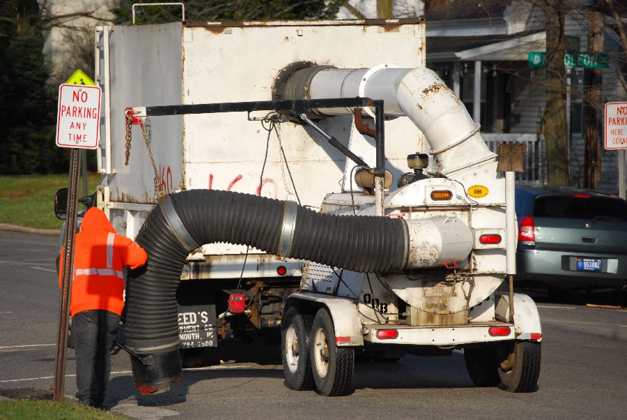 pipes being attached to a garbage truck by workers