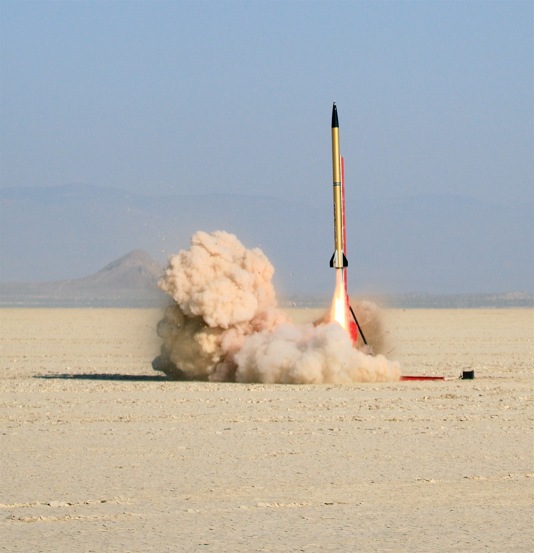 a small rocket with a long trailing tail is in the air