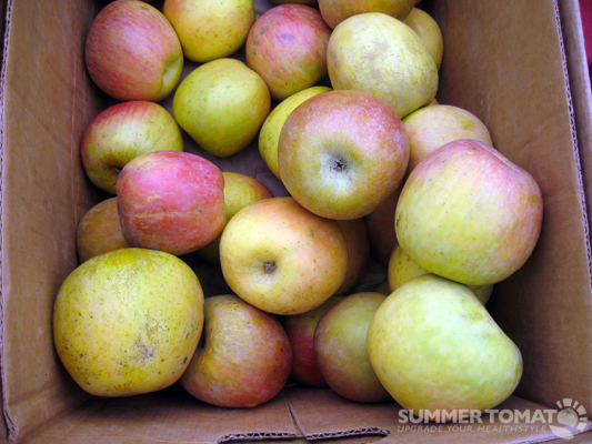 a brown box full of yellow and red apples