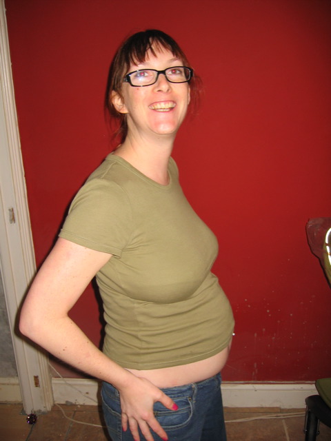 the pregnant woman smiles while holding her hands on her hip