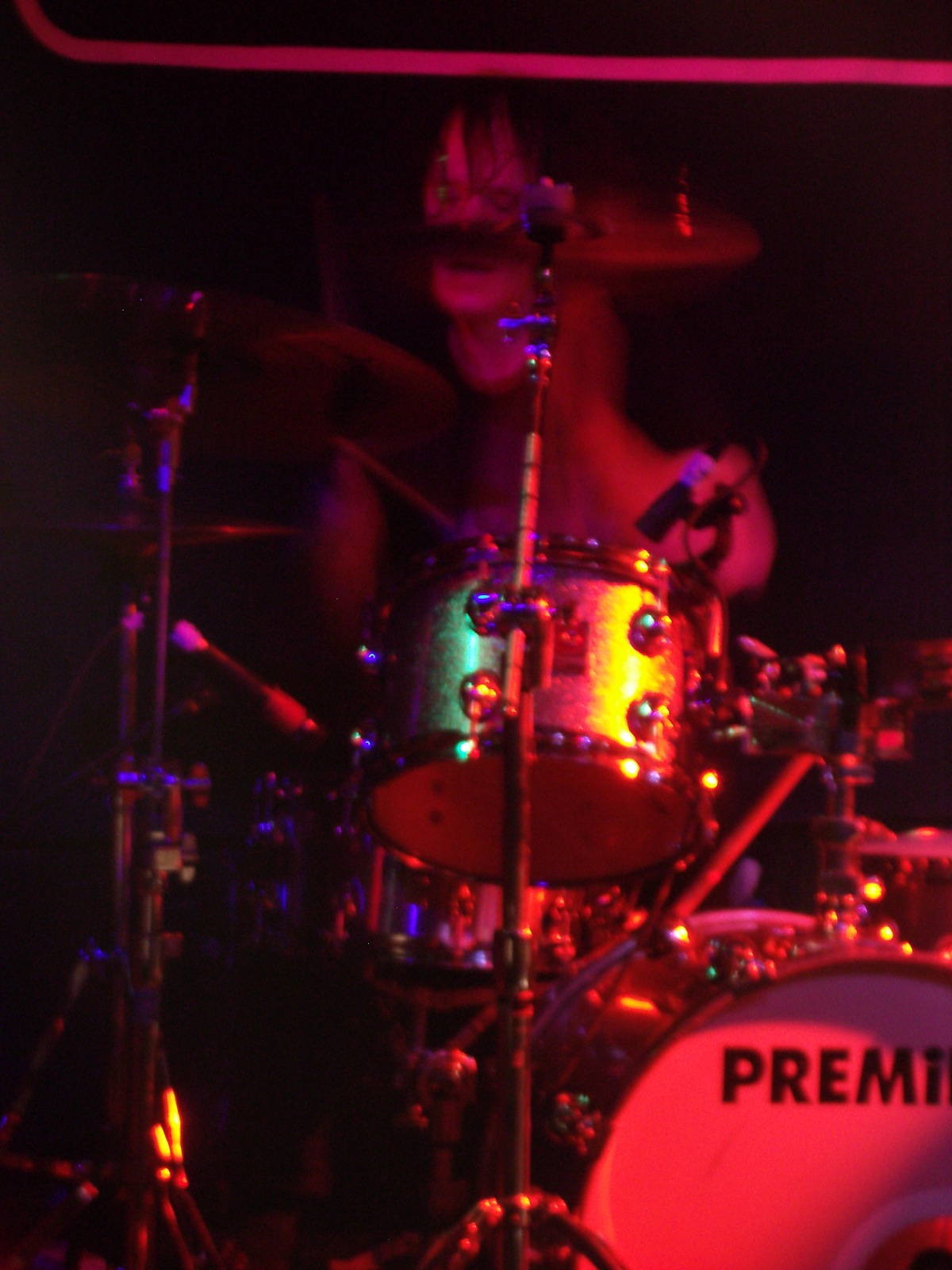 a girl behind a drum set performing in a dark room