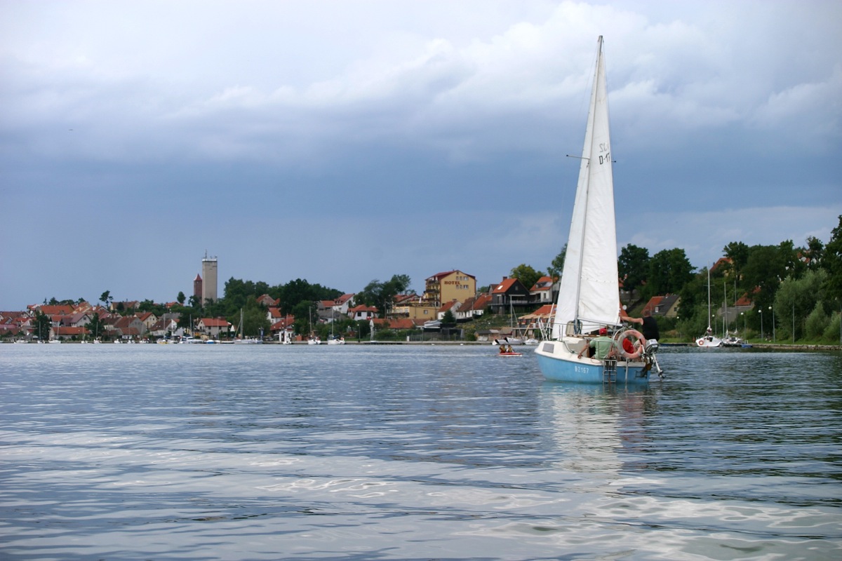 a small sailboat with people on board in the water