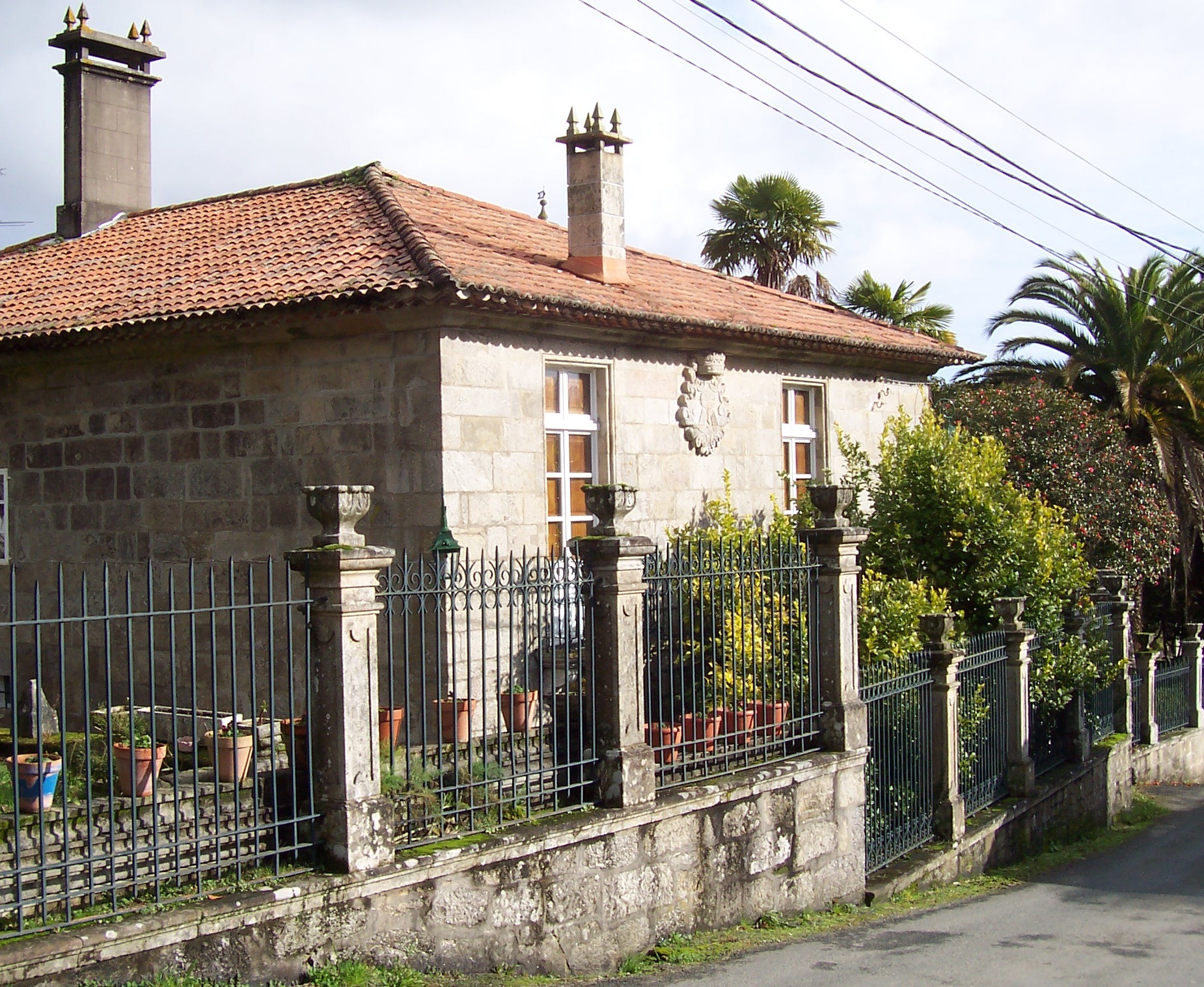 an old house behind a fence with pots on it